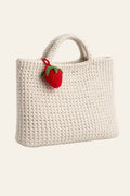 Crochet strawberry bag charm pattern — handmade red amigurumi strawberry keychain with green leaf top clipped to a tote