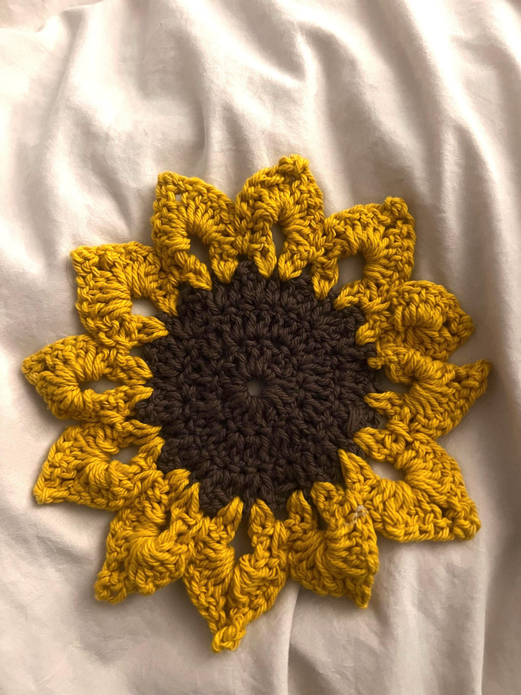 Crochet sunflower coaster styled on a kitchen counter as summer home decor and surface protection