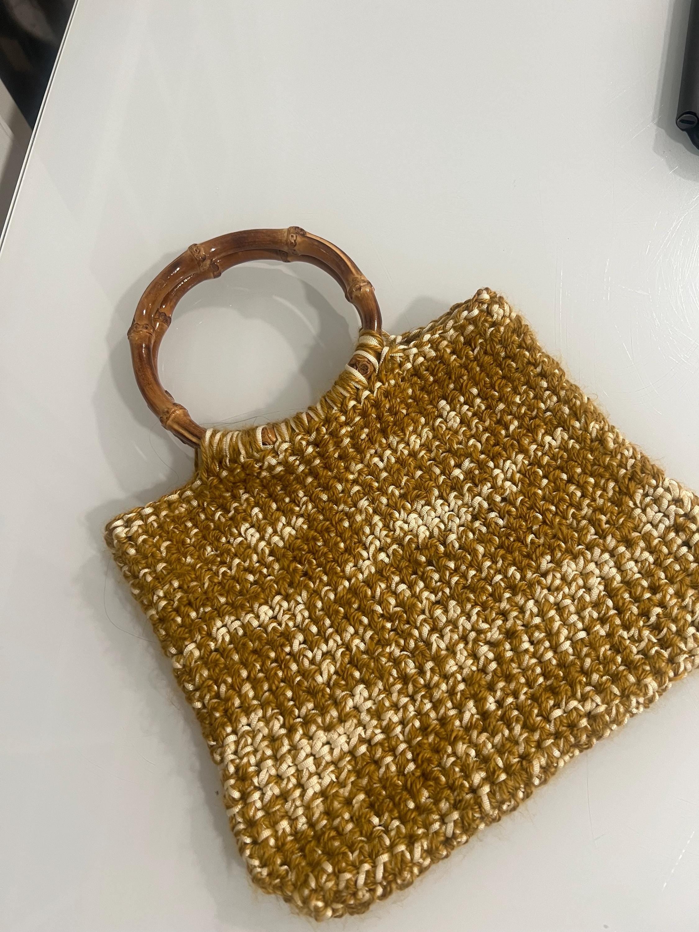 Crochet bamboo handle tote bag held by hand to show the 10 by 8 inch finished size and round bamboo ring handles